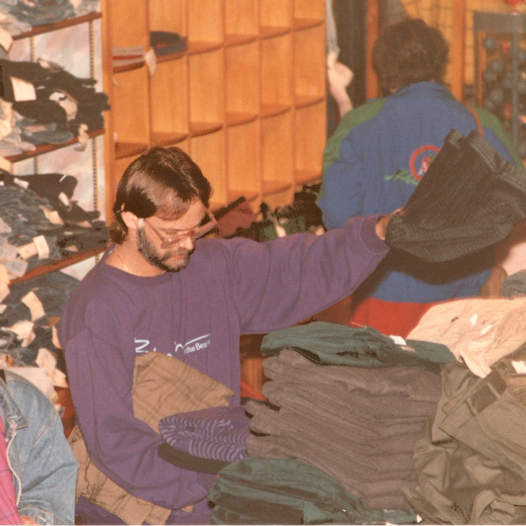 Man folding clothes in a store wearing a Bimini sweatshirt